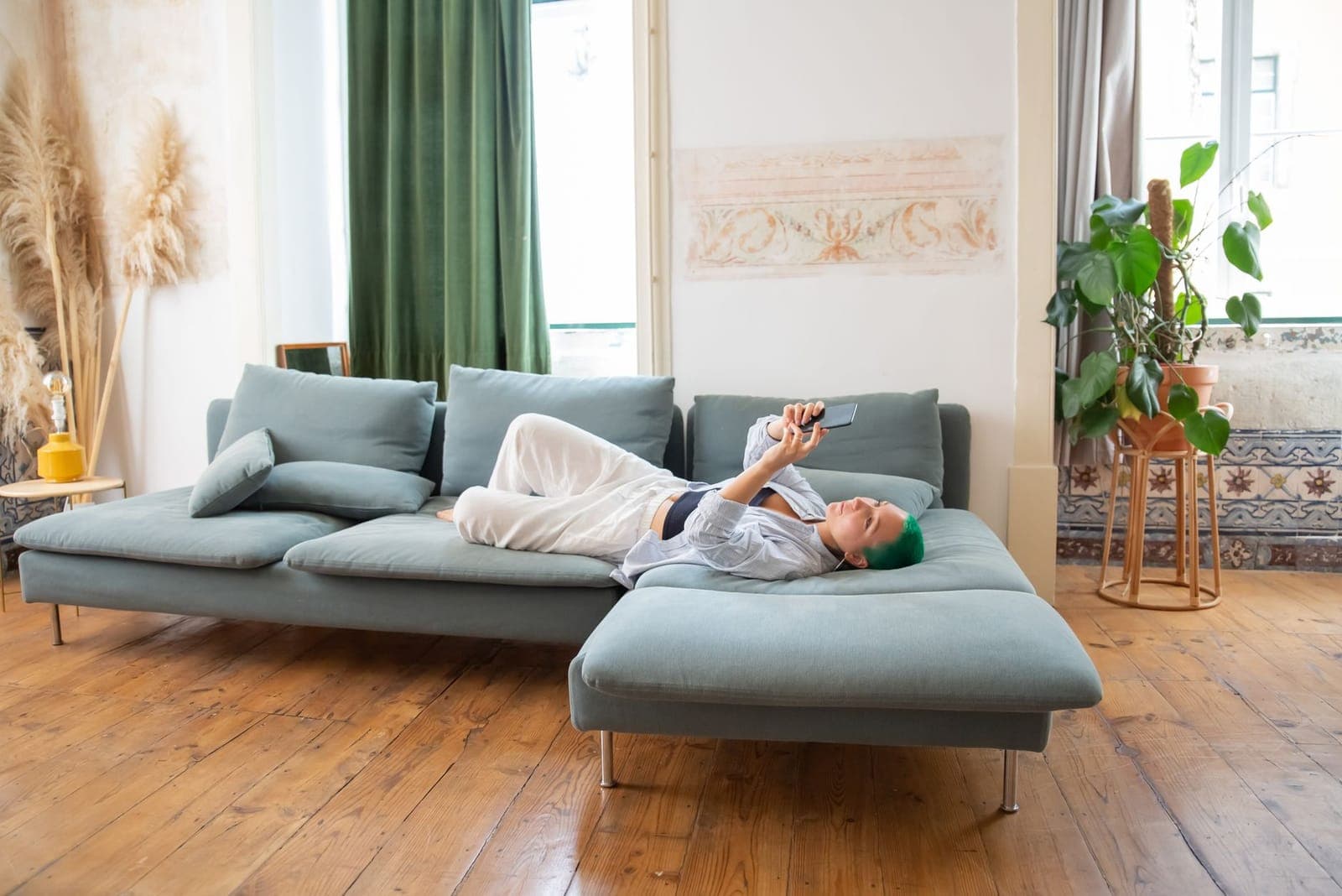 A person relaxing on a sofa at home using a smartphone