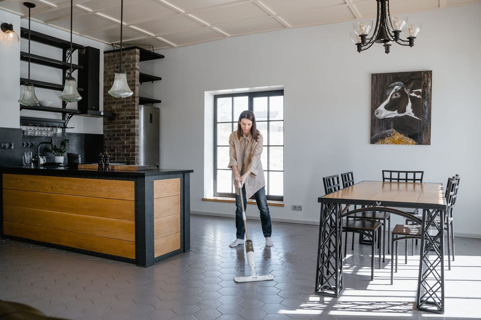 A person mopping a tiled kitchen and dining floor