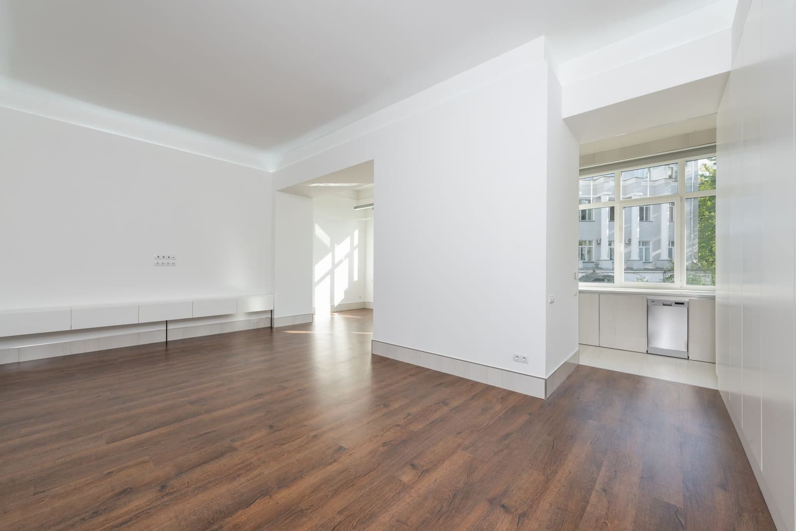 A bright apartment interior with wooden flooring and large windows