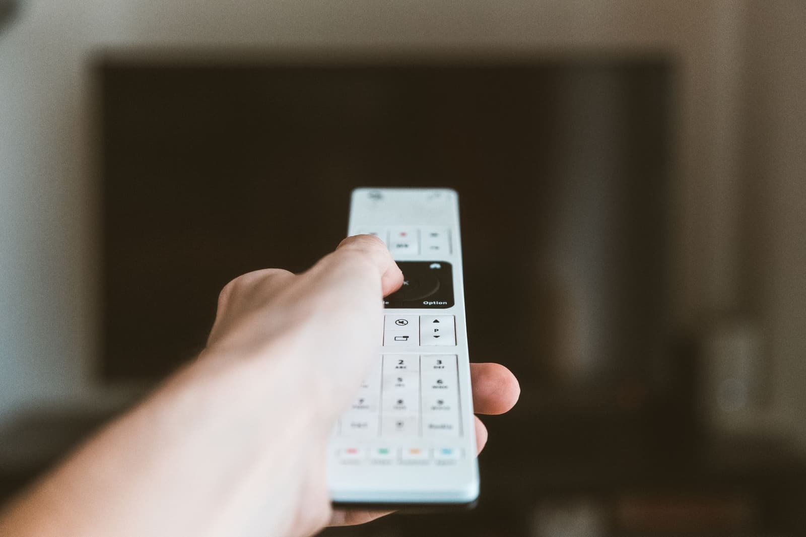 A hand using a remote control at home