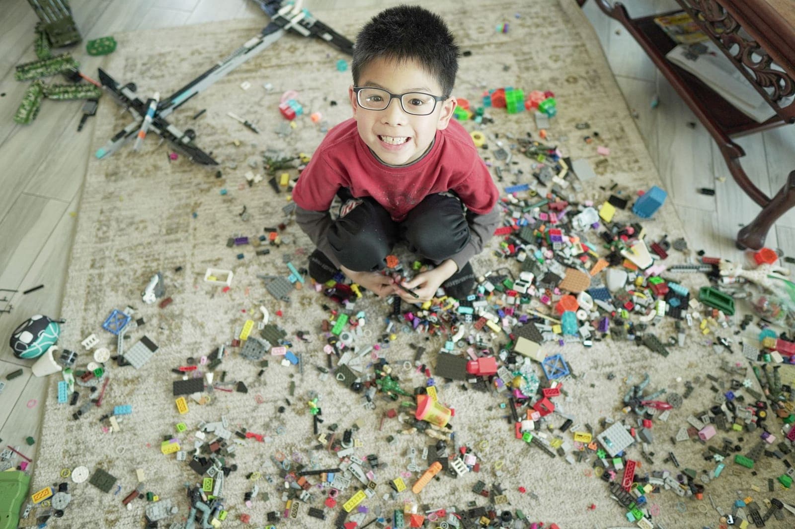 A child sitting among colorful building blocks scattered across a carpet