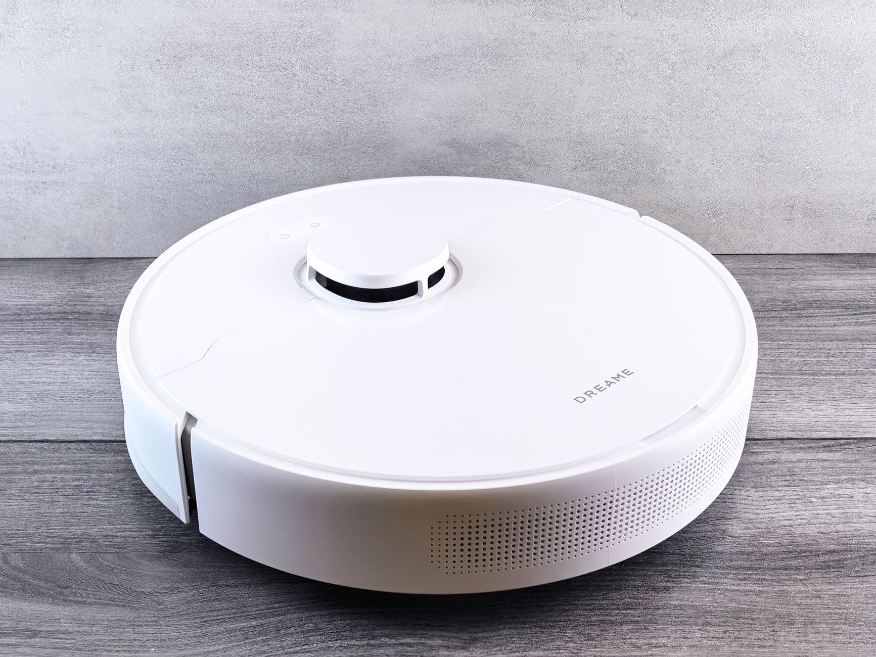 A white robot vacuum on a wooden floor