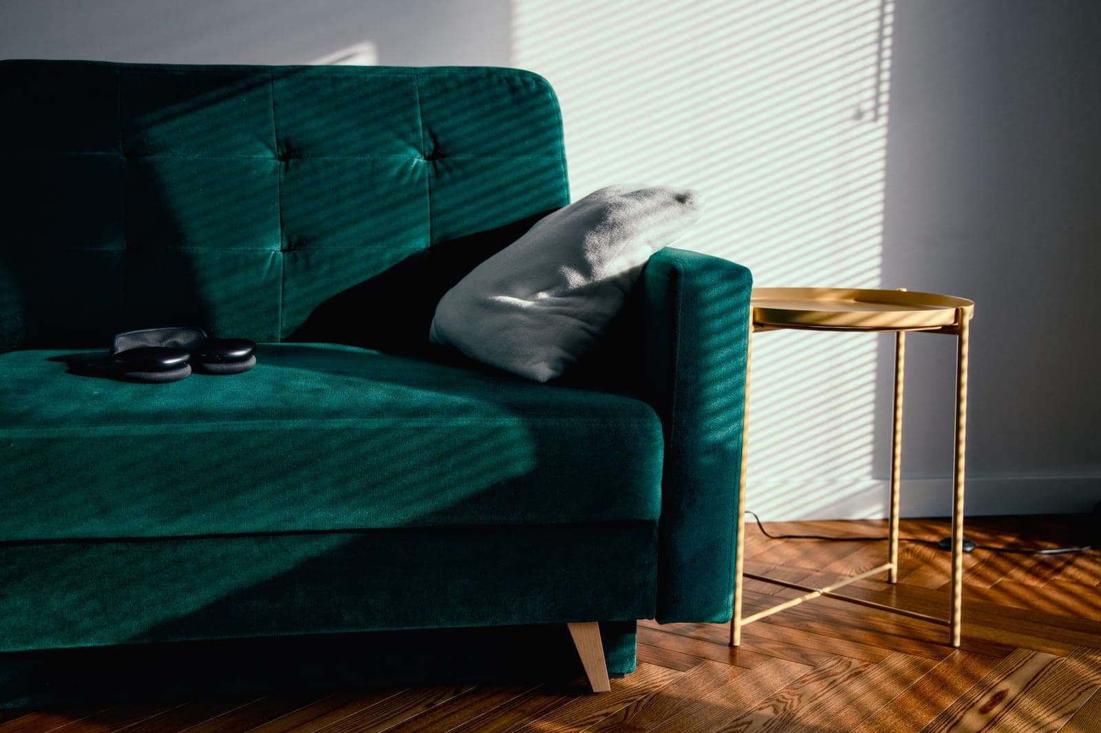 A sunlit living room with a green velvet sofa