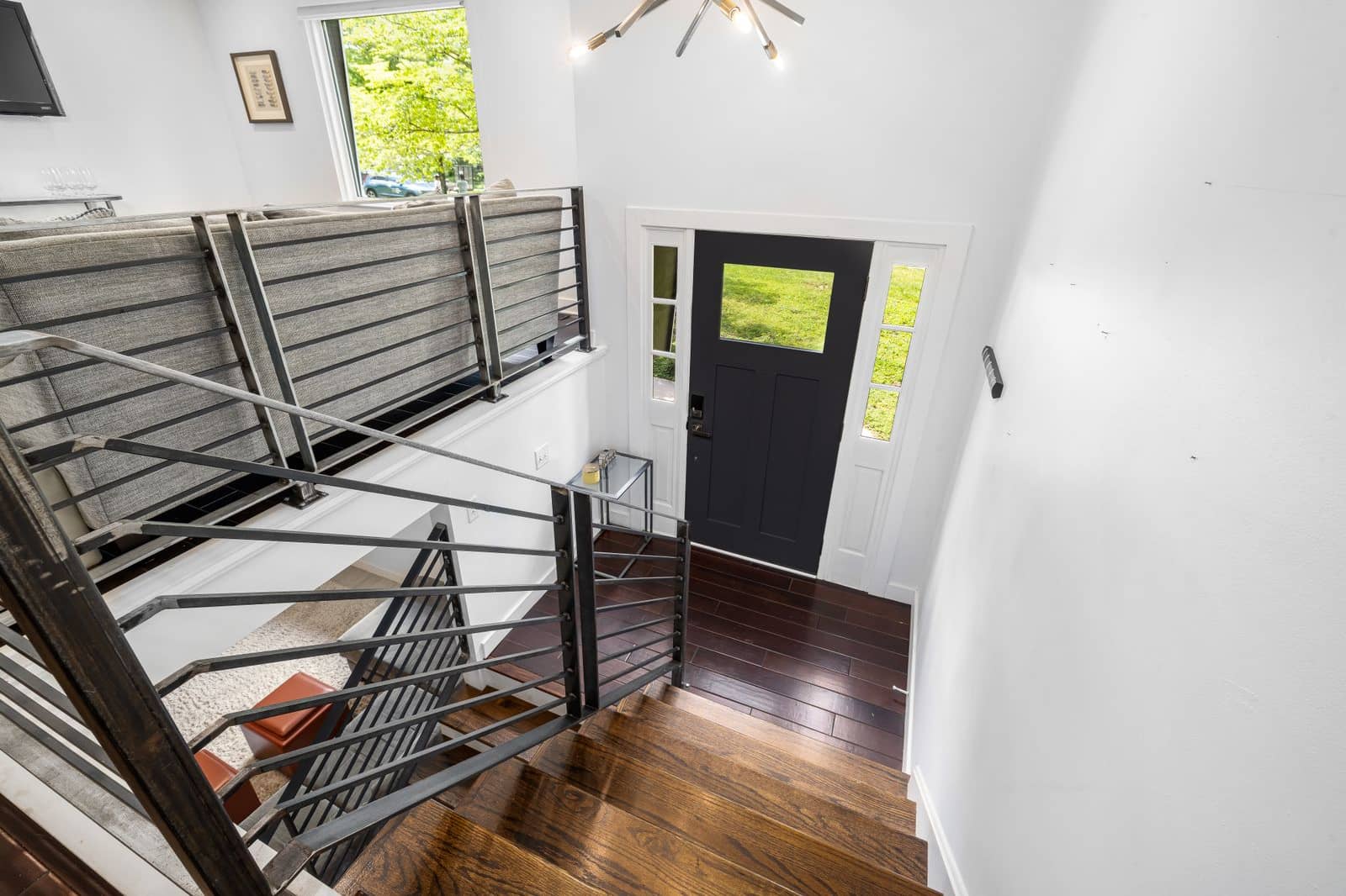 A staircase seen from the upper landing of a home, looking down to the front door and hall