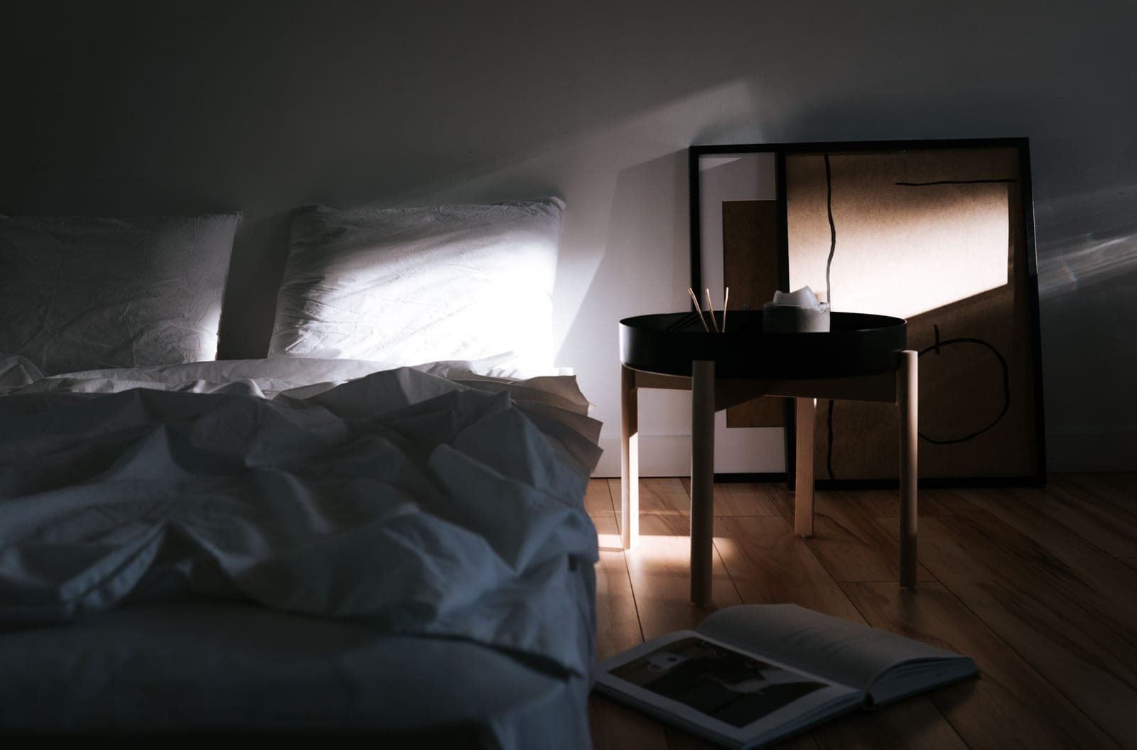 A simple bedroom with a wooden floor in morning light